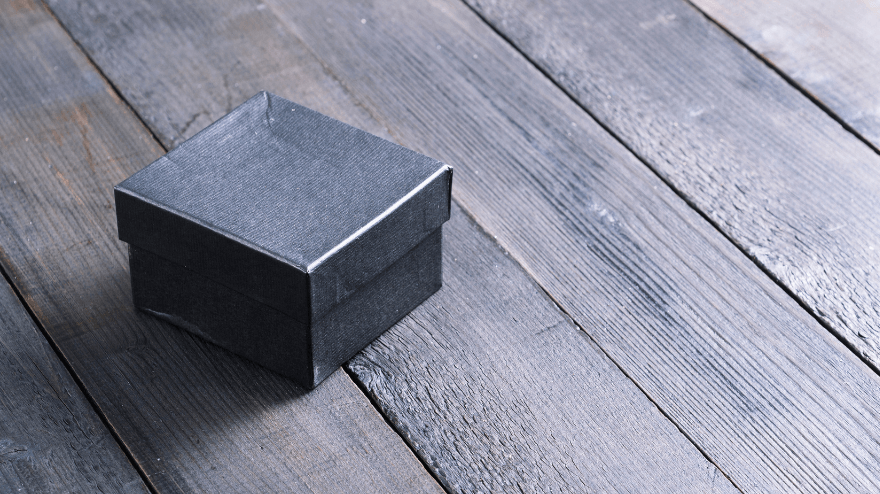 A closed black box on a wood slat floor.